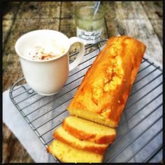 a loaf of bread sitting on top of a cooling rack next to a cup of coffee