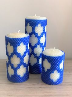 three blue and white candles sitting on top of a wooden table next to each other