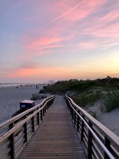 a wooden walkway leading to the beach at sunset