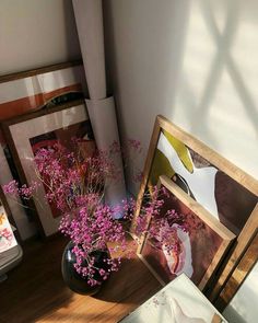 a vase filled with purple flowers sitting on top of a wooden table next to pictures