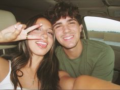 a man and woman sitting in the back seat of a car posing for a photo