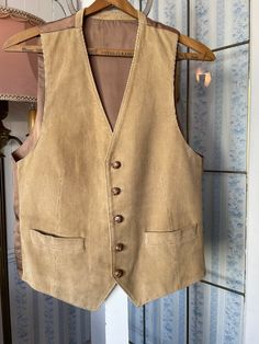 This vest was made in Poland from soft, fine waled, 100 per cent cotton corduroy in tan beige. It has the original turtle buttons in the front, two front pockets and is fully lined. The back is made from silky modal in light brown. Marked size 40. The measurements, taken with the vest lying flat, are: shoulder to shoulder, 12 inches; armpit to armpit, 20 inches; length, 25 inches in front and 22 inches in back; bottom edge, 18 inches. Please note that some of the buttons are showing some wear and tear, but overall the vest is in good vintage condition. Luxury Beige Vest Outerwear, Vintage Beige Vest With Pockets, Beige Vintage Vest With Pockets, Classic Brown Cotton Vest, Vintage Beige Workwear Vest, Corduroy Waistcoat, Corduroy Vest, Beige Vest, Brown Vest