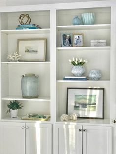 white bookcases with vases and pictures on them