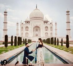 a man kneeling down next to a woman in front of a taj - e