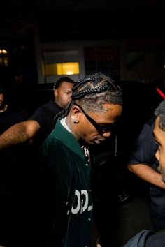 a man with dreadlocks talking to another man in a black jacket and green shirt