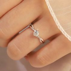 a woman's hand with a diamond ring on top of her finger, wearing a white dress