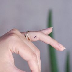 a woman's hand with a tiny bird tattoo on her left index and finger