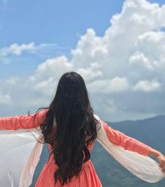 a woman standing on top of a mountain with her arms spread out to the side