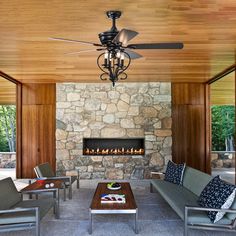 a living room filled with furniture and a fire place in front of a stone wall