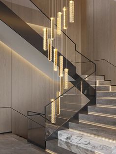 an elegant staircase with glass chandelier and marble steps leading up to the second floor