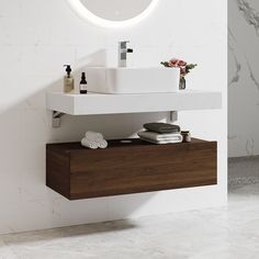 a white sink sitting under a round mirror next to a wall mounted faucet