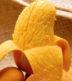 a peeled banana sitting on top of an orange peel next to another sliced piece of fruit