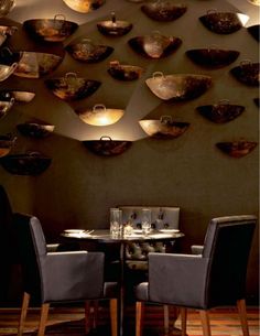 a dining room with several bowls hanging on the wall and chairs around tables in front of them