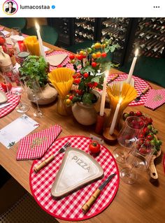 the table is set with red and white checkered placemats, plates, utensils and candles