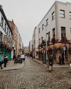 people are walking down an old cobblestone street