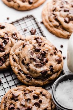 chocolate chip cookies cooling on a wire rack next to a glass of milk and some sugar