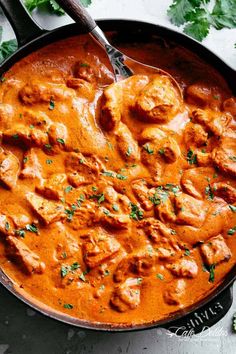 a skillet filled with chicken curry and garnished with parsley