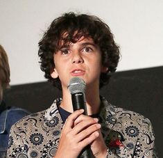 a young man holding a microphone in front of his face while standing next to another person