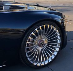 a black sports car parked on the side of the road with chrome rims and spokes