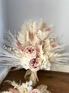 a bouquet of flowers sitting on top of a wooden table next to another bouquet with white and pink flowers