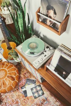 a record player sitting on top of a wooden table next to a potted plant