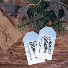 two christmas gift tags sitting on top of a wooden table