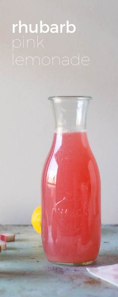 a pink lemonade in a glass pitcher next to some crayons on a table