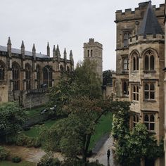 an aerial view of a building with trees in the foreground and people walking around