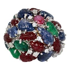 This is part of Chairish’s Fine Jewelry assortment.  Huge Tutti Frutti 18K Ring, Emeralds, Rubies, Sapphires and Diamonds  This huge Tutti Frutti Ring is special due to its size and the gorgeous carved gemstone leaves. There are Rubies, Emeralds, Sapphires with Diamonds interspersed throughout. Tutti frutti jewelry is rare and special as most of it was made in the 1920's-1930's by famous Jewelry houses and a short revival of Tutti frutti again in the 1960's when this ring was produced. I rarely Famous Jewelry, Diamonds Ring, Tutti Frutti, Cocktail Rings, Diamond Rings, 1960s, Ruby, Emerald, Jewelry Rings