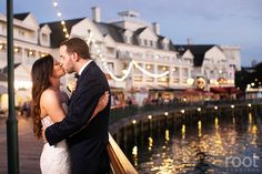 a bride and groom kissing in front of the water at their wedding reception on the boardwalk