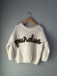 a white sweater with leopard print on the chest and words that spell out'love '