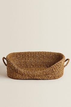 a woven basket with handles on a white background, it is empty and ready to be used for storage