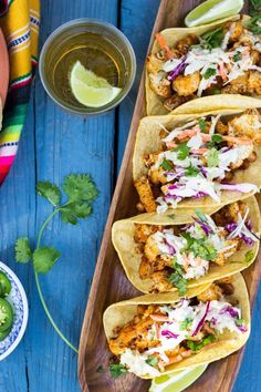 three tacos on a wooden platter with salsa and jalapenos next to it