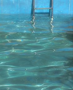 a chair sitting in the middle of a pool with clear water and blue walls behind it