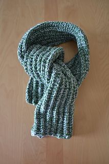 a green and white knitted scarf sitting on top of a wooden table