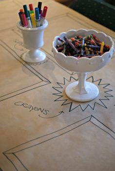 crayons are in a bowl on a table next to a cup full of crayons