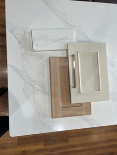 a white kitchen counter top with two square knobs and a cabinet door on one side