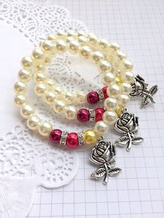 two bracelets with beads and charms on top of a white doily tablecloth