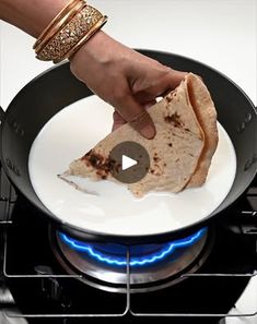 a person cooking food in a pan on top of a stove with a blue flame