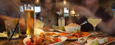 plates and bowls of food on a table with people in the background at a restaurant