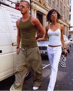 the man and woman are walking down the street in front of a white van together