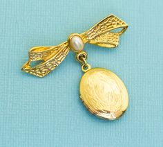 This is a gold tone oval-shaped pendant with ribbon and faux pearl. GENERAL DESCRIPTION Vintage Gold Tone Ribbon Locket Oval Victorian Brooch Color: Gold Tone, White Brand: NA Size: Last photo includes measurements of brooch. If you have any questions please feel free to message us! White Brand, Vintage Gold, Locket, Faux Pearl, Brooch Pin, Ribbon, Gold Tones, Band, Pendant