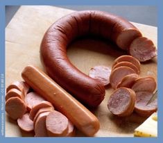 a wooden cutting board topped with sliced sausages next to a knife and pepperoni