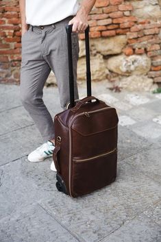 Upgrade your travel experience with our Handmade Italian Leather Rolling Suitcase, a perfect blend of luxury and functionality. Crafted from the finest Tuscan vacchetta leather, this rolling suitcase showcases the rich heritage and artisanal skill of Montepulciano. Designed for both men and women, this carry-on bag combines elegance with practicality, making it an ideal choice for both business trips and vacations. Features: ◉ Premium Material: Made from 100% genuine Tuscan vacchetta leather, ce Luxury Leather Rectangular Backpack For Trips, Luxury Rectangular Leather Backpack For Trips, Luxury Leather Backpack For Trips, Classic Leather Travel Accessories With Luggage Sleeve, Luxury Rectangular Travel Accessories Case, Brown Leather Luggage For Overnight Trips, Luxury Cognac Laptop Bag For Travel, Luxury Travel Laptop Bag In Cognac, Brown Rectangular Travel Case