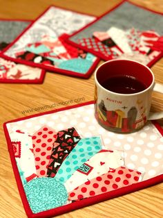 a cup of coffee sitting on top of a wooden table next to patchwork coasters