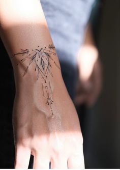 a woman's arm with a tattoo on it and her hand in the background