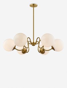 a brass chandelier with five white glass globes hanging from the ceiling,