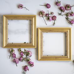 three gold frames with pink flowers on a white surface next to each other and one is empty