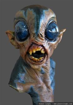 an alien head with blue eyes and teeth