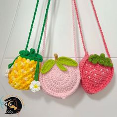 three crocheted strawberries hanging from hooks